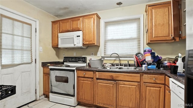 17 E 31st St, Richmond, VA 23224 - kitchen featuring white appliances, dark countertops, light tile patterned floors, and brown cabinets