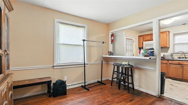 17 E 31st St, Richmond, VA 23224 - kitchen with a kitchen breakfast bar, wood finished floors, a baseboard heating unit, brown cabinetry, and tile counters