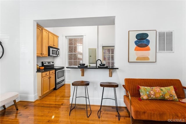 603 N Allen Ave Unit U1B, Richmond, VA 23220 - kitchen with stainless steel appliances, a breakfast bar area, dark countertops, light wood-style flooring, and a peninsula