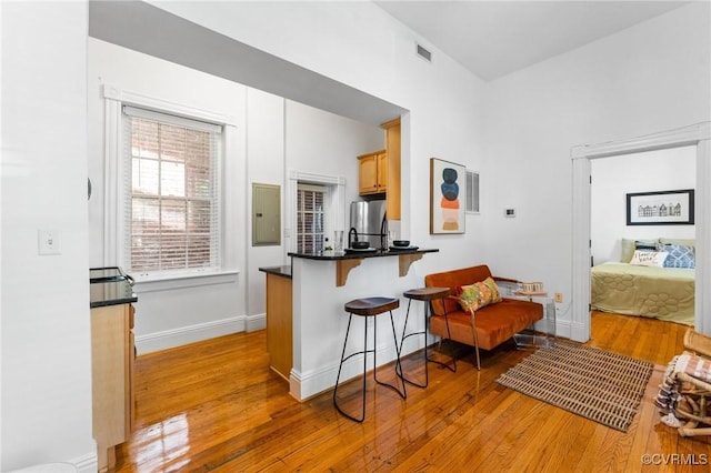 603 N Allen Ave Unit U1B, Richmond, VA 23220 - kitchen featuring freestanding refrigerator, light wood-type flooring, electric panel, a breakfast bar area, and dark countertops