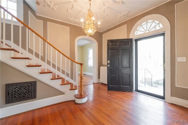 1602 Brandon Ave, Petersburg, VA 23805 - entrance foyer featuring arched walkways, radiator heating unit, wood-type flooring, crown molding, and stairway