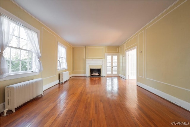 1602 Brandon Ave, Petersburg, VA 23805 - unfurnished living room featuring radiator, a decorative wall, radiator heating unit, a fireplace with flush hearth, and hardwood / wood-style floors