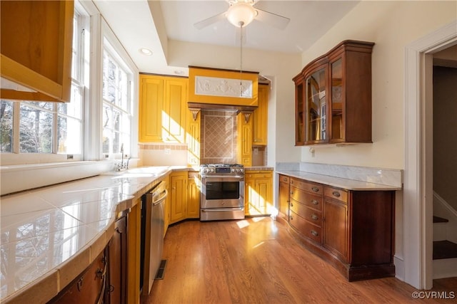 1602 Brandon Ave, Petersburg, VA 23805 - kitchen with appliances with stainless steel finishes, light wood-style floors, light countertops, and glass insert cabinets