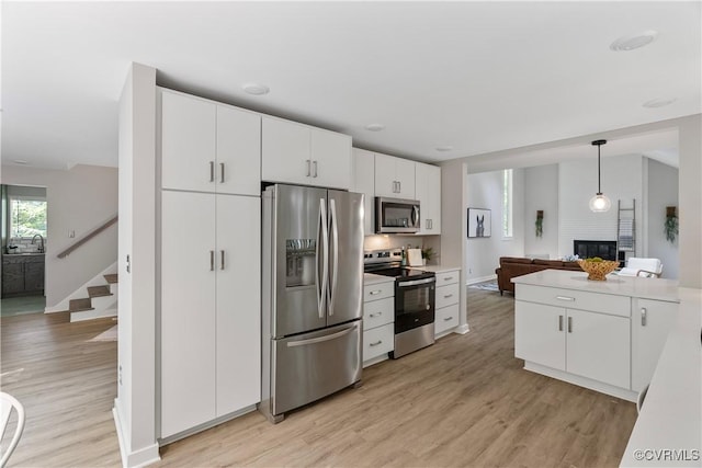 4458 Old Fox Trl, Chesterfield, VA 23112 - kitchen featuring appliances with stainless steel finishes, light wood-style flooring, a fireplace, white cabinets, and light countertops