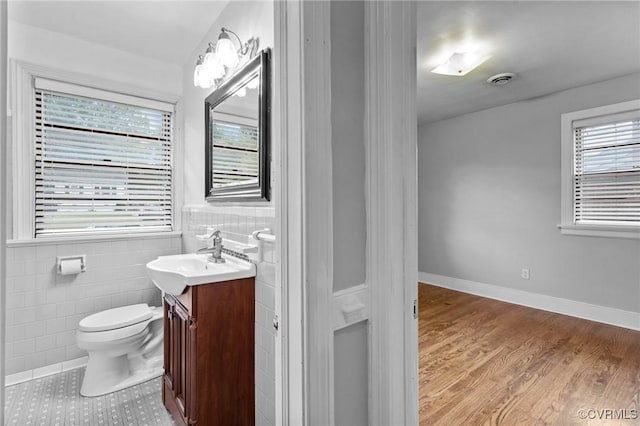 3205 Birchbrook Rd, Henrico, VA 23228 - bathroom with vanity, tile walls, plenty of natural light, a wainscoted wall, and wood finished floors