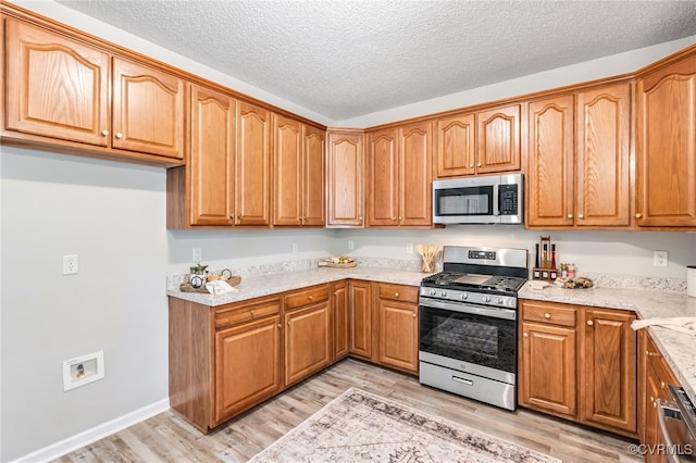 6118 Pond Grass Rd, Mechanicsville, VA 23111 - kitchen with stainless steel appliances, light wood-style flooring, brown cabinets, and a textured ceiling