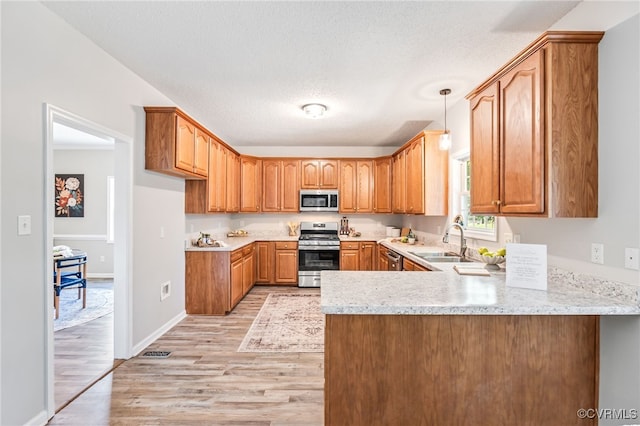 6118 Pond Grass Rd, Mechanicsville, VA 23111 - kitchen featuring appliances with stainless steel finishes, a peninsula, light wood-style flooring, brown cabinetry, and decorative light fixtures