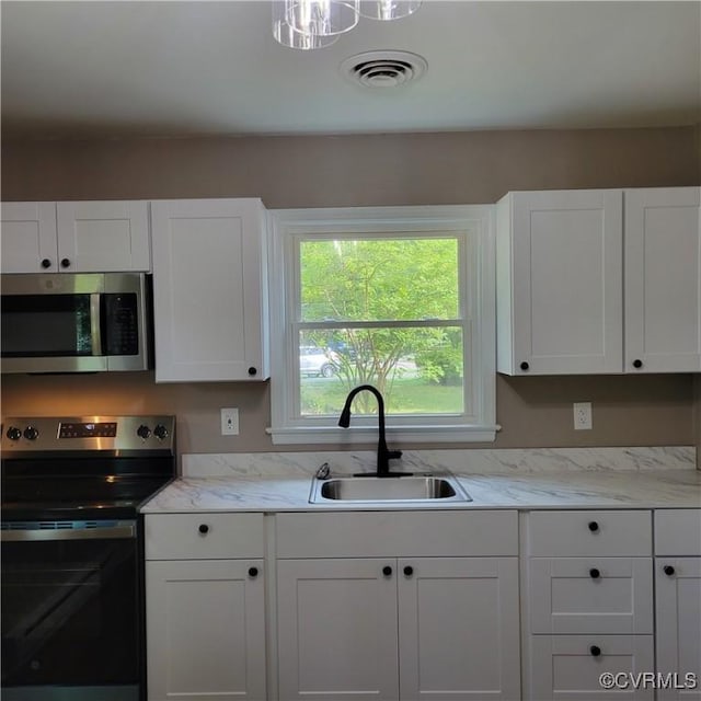 3017 Wright Rd, Petersburg, VA 23805 - kitchen with appliances with stainless steel finishes, white cabinetry, and light stone counters