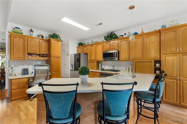 9316 Crossover Dr, Mechanicsville, VA 23116 - kitchen with appliances with stainless steel finishes, light countertops, a kitchen bar, and light wood-type flooring