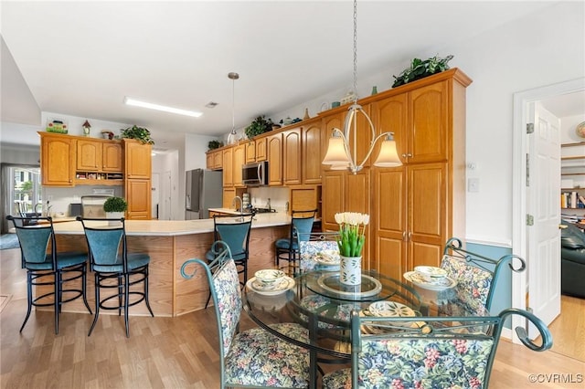 9316 Crossover Dr, Mechanicsville, VA 23116 - kitchen with appliances with stainless steel finishes, light wood-style floors, a kitchen bar, light countertops, and brown cabinetry