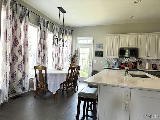 43314 Fullerton St, Ashburn, VA 20147 - kitchen featuring stainless steel microwave, decorative backsplash, light stone countertops, tile patterned flooring, and recessed lighting