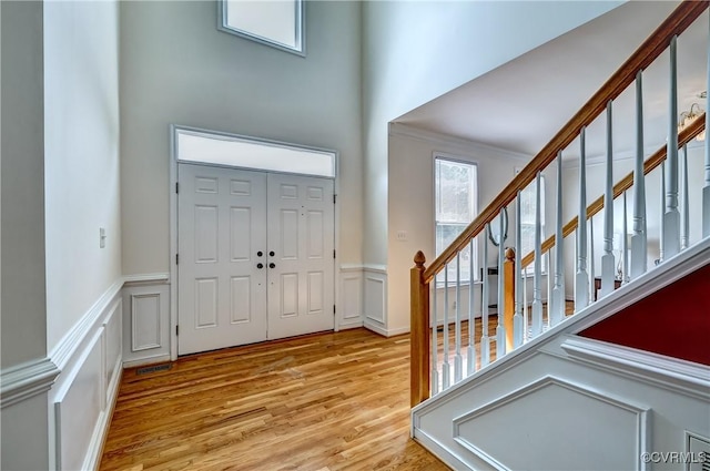 5408 Woolshire Dr, Glen Allen, VA 23059 - foyer featuring light wood finished floors, a towering ceiling, stairway, wainscoting, and a decorative wall