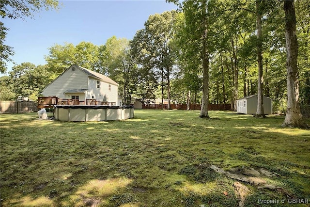 8187 Lord Fairfax Cir, Gloucester, VA 23061 - fenced backyard with a storage unit, a covered pool, a deck, and view of wooded area