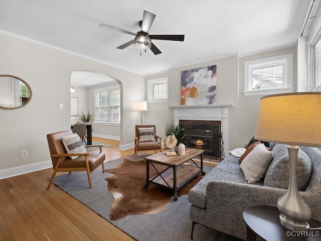 3303 Woodrow Ave, Richmond, VA 23222 - living room featuring arched walkways, wood finished floors, a ceiling fan, a brick fireplace, and crown molding