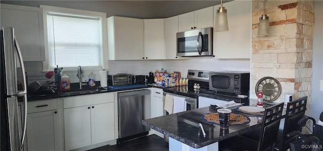 3908 Decatur St, Richmond, VA 23224 - kitchen featuring stainless steel appliances, white cabinets, a peninsula, tasteful backsplash, and a kitchen bar