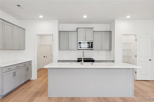 124 Steyland St, Ashland, VA 23005 - kitchen with gray cabinets, stainless steel microwave, backsplash, light wood-type flooring, and recessed lighting