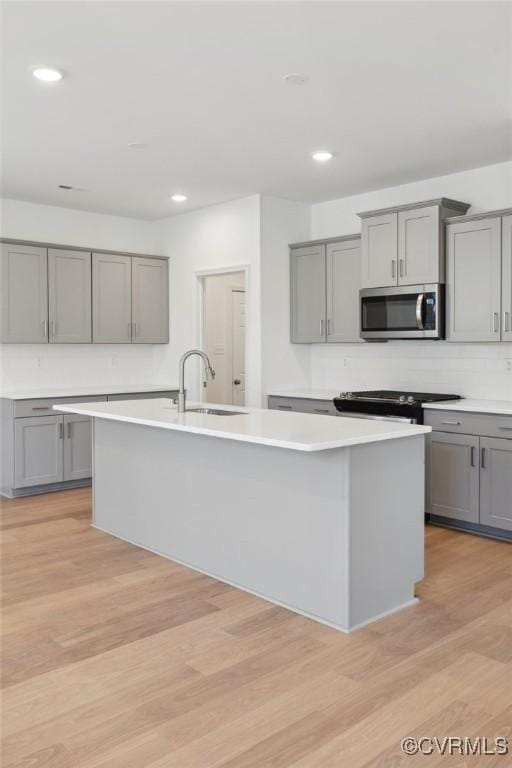 124 Steyland St, Ashland, VA 23005 - kitchen featuring stainless steel microwave, gray cabinetry, a center island with sink, light countertops, and recessed lighting