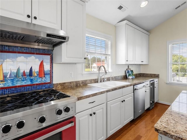 621 Fort Lowry Ln, Dunnsville, VA 22454 - kitchen with under cabinet range hood, range, stainless steel dishwasher, light wood finished floors, and decorative backsplash