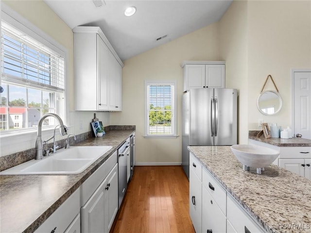 621 Fort Lowry Ln, Dunnsville, VA 22454 - kitchen with stainless steel appliances, white cabinets, vaulted ceiling, and light wood-type flooring