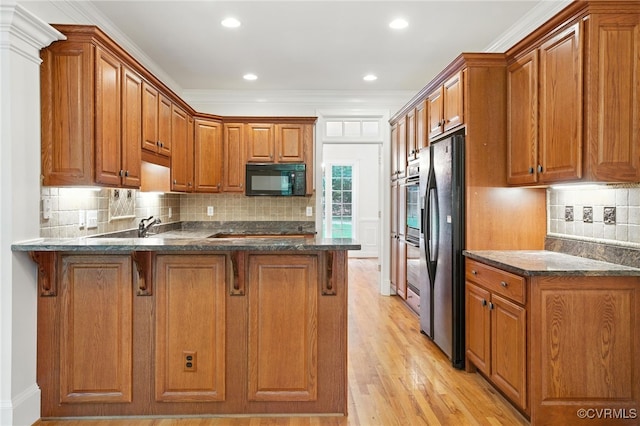 3007 Tranbycroft Way, Sandy Hook, VA 23153 - kitchen with black microwave, a peninsula, stainless steel refrigerator with ice dispenser, brown cabinets, and dark stone countertops