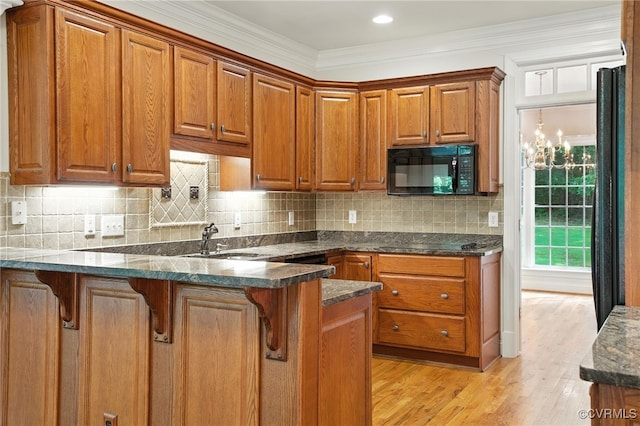 3007 Tranbycroft Way, Sandy Hook, VA 23153 - kitchen featuring black appliances, a peninsula, brown cabinets, light wood-type flooring, and decorative backsplash