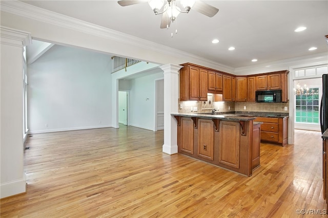 3007 Tranbycroft Way, Sandy Hook, VA 23153 - kitchen with black microwave, a ceiling fan, a breakfast bar area, a peninsula, and light wood finished floors