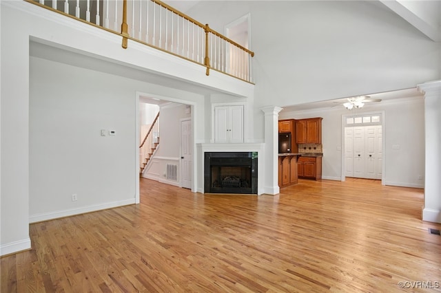 3007 Tranbycroft Way, Sandy Hook, VA 23153 - unfurnished living room with a ceiling fan, a high ceiling, ornate columns, light wood-type flooring, and a fireplace