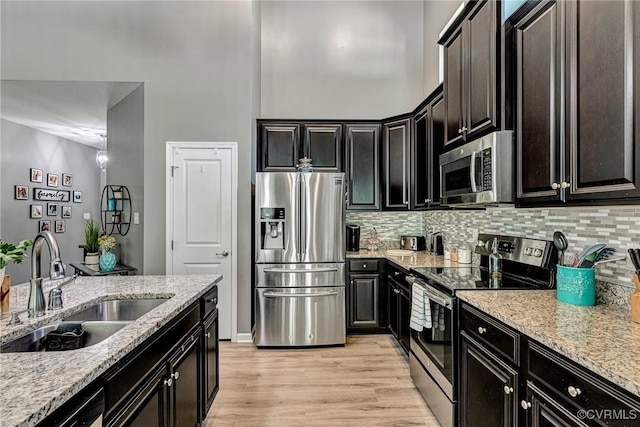 5858 Pilmour Dr, Providence Forge, VA 23140 - kitchen with stainless steel appliances, decorative backsplash, light wood-style flooring, light stone countertops, and a towering ceiling