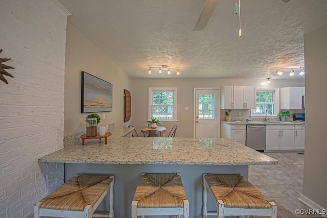 1300 Hyner Cir, Sandston, VA 23231 - kitchen with stainless steel dishwasher, rail lighting, a kitchen bar, white cabinetry, and a textured ceiling