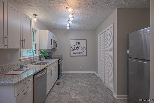1300 Hyner Cir, Sandston, VA 23231 - kitchen with stainless steel appliances, rail lighting, a textured ceiling, white cabinetry, and light stone countertops