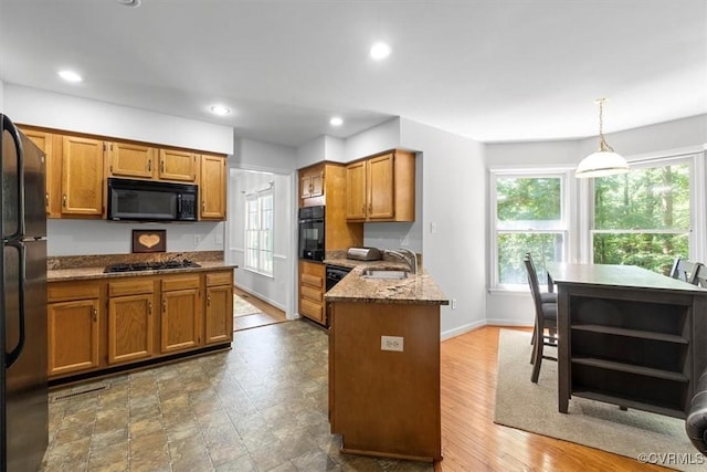 3019 Ramsey Dr, Chester, VA 23831 - kitchen featuring black appliances, a peninsula, brown cabinets, dark stone counters, and recessed lighting