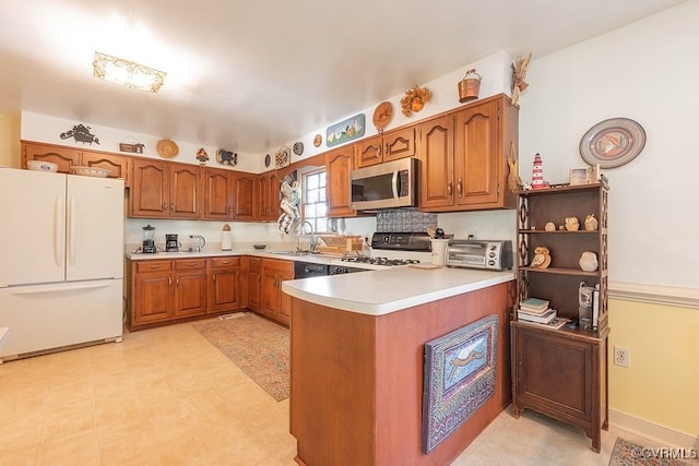 570 Three Chopt Rd, Manakin Sabot, VA 23103 - kitchen featuring freestanding refrigerator, stainless steel microwave, gas range oven, a peninsula, and brown cabinetry