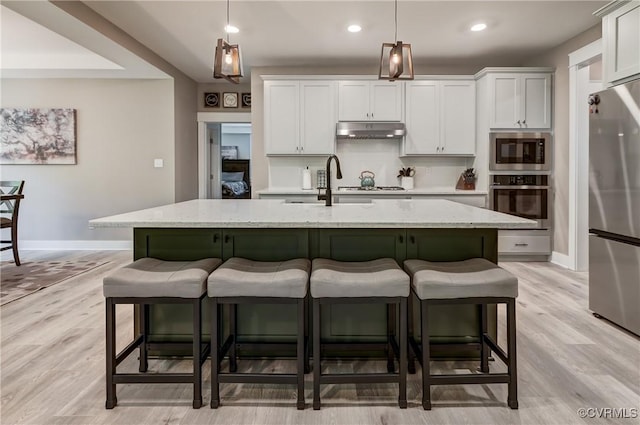 3016 Maple Grove Ln, Powhatan, VA 23139 - kitchen with appliances with stainless steel finishes, under cabinet range hood, a kitchen breakfast bar, a kitchen island with sink, and recessed lighting