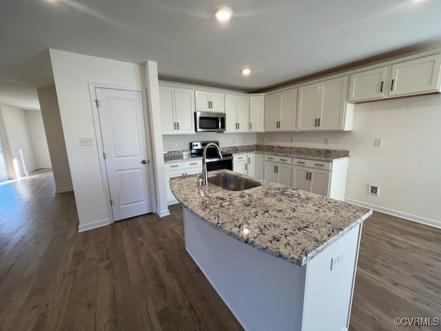 4917 Bailey Woods Ln, Midlothian, VA 23112 - kitchen with stainless steel microwave, an island with sink, light stone counters, dark wood-style floors, and recessed lighting