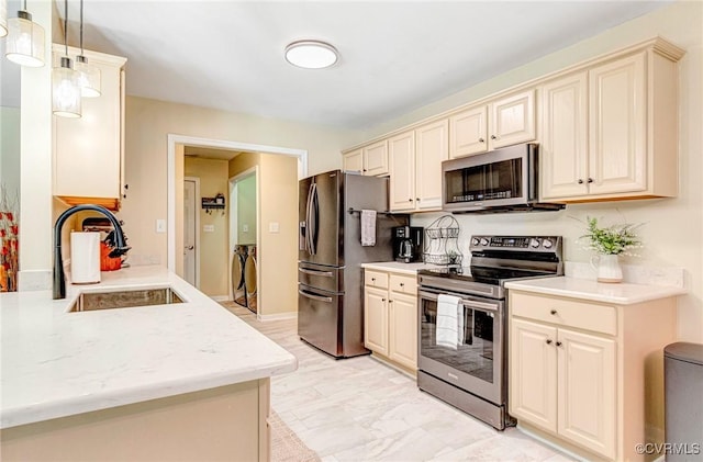 5773 S Jessup Rd, Chesterfield, VA 23832 - kitchen featuring appliances with stainless steel finishes, separate washer and dryer, cream cabinets, light marble finish floors, and hanging light fixtures