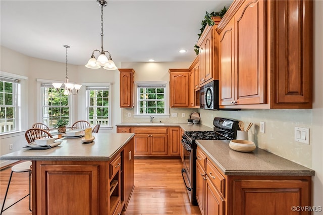 6125 Trinity Church Rd, Dinwiddie, VA 23833 - kitchen featuring stainless steel gas range, black microwave, a chandelier, light wood-style floors, and a breakfast bar area
