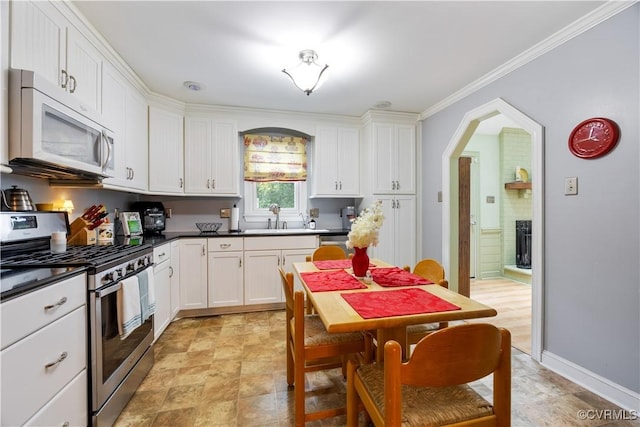 4310 Courthouse Rd, Prince George, VA 23875 - kitchen featuring stainless steel range with gas cooktop, white microwave, white cabinets, dark countertops, and arched walkways