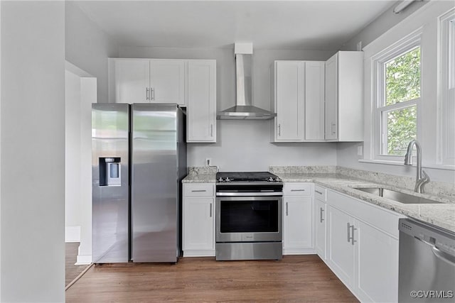 3406 Lawson St, Richmond, VA 23224 - kitchen featuring appliances with stainless steel finishes, wall chimney range hood, white cabinetry, and light stone counters