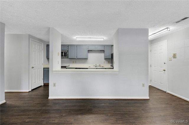 7604 Roscommon Ct Unit 2403, Henrico, VA 23228 - kitchen featuring stainless steel microwave, a textured ceiling, dark wood finished floors, light countertops, and gray cabinetry
