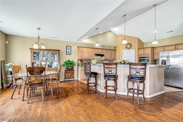 8125 Janice Ave, Mechanicsville, VA 23111 - kitchen with stainless steel appliances, under cabinet range hood, wood finished floors, backsplash, and a kitchen bar