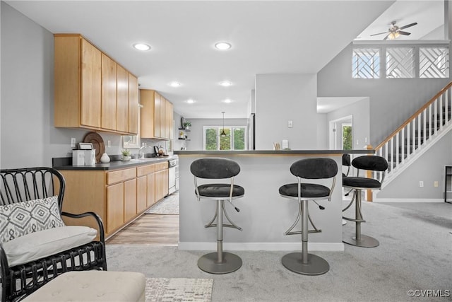 9712 Kingussle Ln, North Chesterfield, VA 23236 - kitchen featuring a kitchen bar, light brown cabinetry, dark countertops, a ceiling fan, and recessed lighting