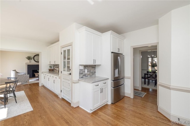10703 Kriserin Cir, Chester, VA 23831 - kitchen featuring stainless steel fridge with ice dispenser, light wood finished floors, a fireplace, white cabinets, and decorative backsplash