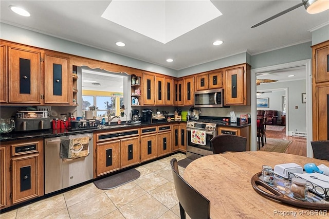 77 Kent Cove Rd, Kilmarnock, VA 22482 - kitchen with appliances with stainless steel finishes, brown cabinetry, ceiling fan, crown molding, and dark countertops