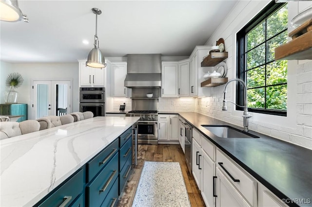 3719 Waverton Dr, Midlothian, VA 23112 - kitchen with stainless steel appliances, wall chimney range hood, open shelves, blue cabinets, and white cabinetry