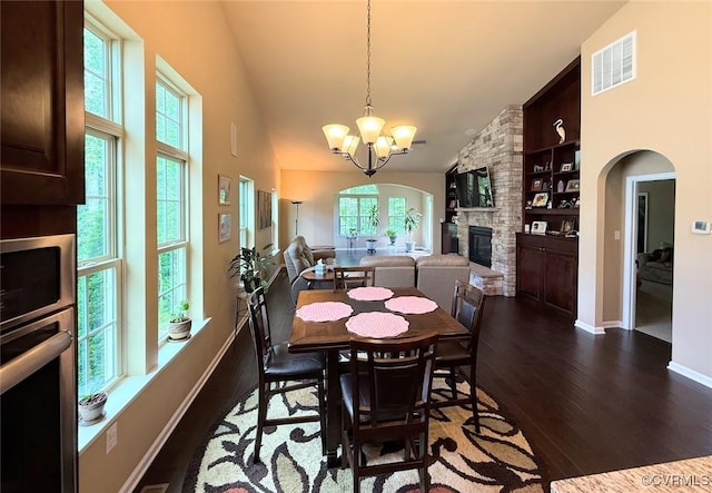 17419 Great Falls Cir, Moseley, VA 23120 - dining space featuring a chandelier, a stone fireplace, dark wood-style floors, arched walkways, and built in features