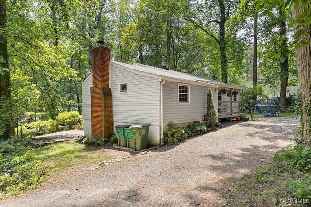 3942 Hickory Rd, Richmond, VA 23235 - view of side of property with a chimney, a trampoline, view of scattered trees, and driveway