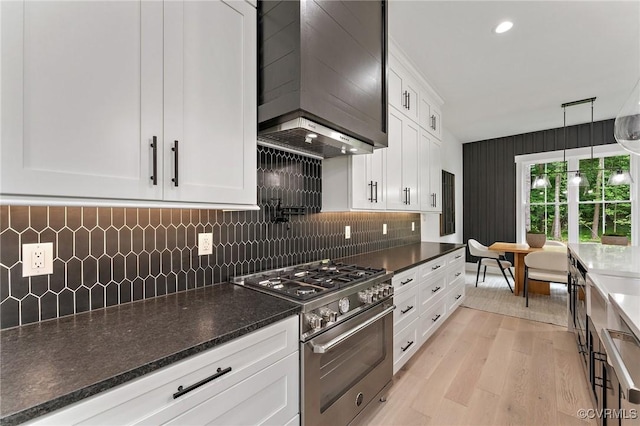 7241 Amarone Way, New Kent, VA 23124 - kitchen featuring stainless steel stove, wall chimney range hood, white cabinetry, light wood-style flooring, and tasteful backsplash