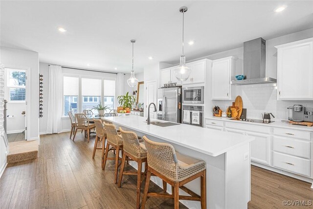 585 Rivanna Hill Rd, Glen Allen, VA 23060 - kitchen featuring wall chimney exhaust hood, stainless steel appliances, a kitchen island with sink, backsplash, and light countertops
