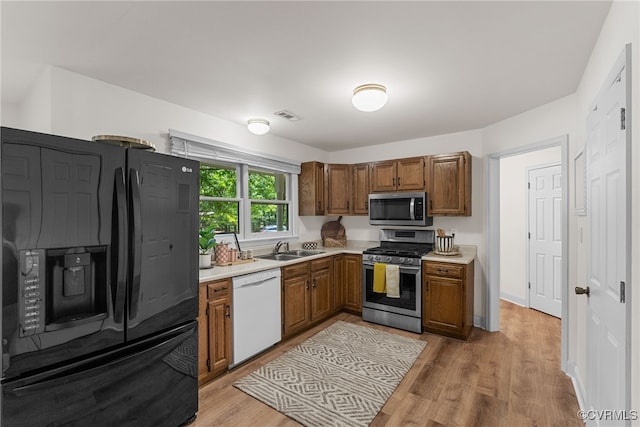 102 Penrith Ct, Williamsburg, VA 23185 - kitchen featuring appliances with stainless steel finishes, light countertops, light wood-type flooring, and brown cabinetry