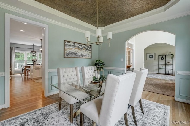 3731 Rivermist Ter, Midlothian, VA 23113 - dining space featuring light wood finished floors, a chandelier, a wainscoted wall, a raised ceiling, and arched walkways
